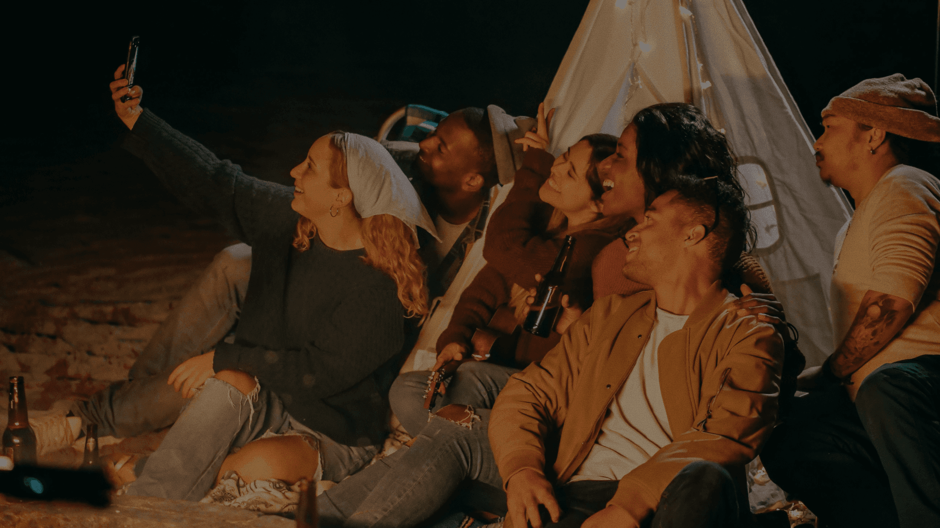 Group of friends taking a selfie inside a glowing tent